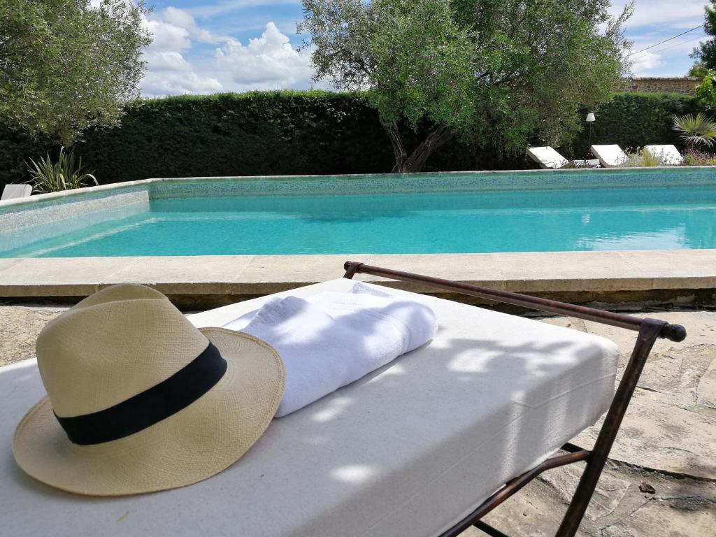 - un chapeau assis sur un banc à côté d'une piscine dans l'établissement Magnifique Bastide 10 chambres, à Deaux