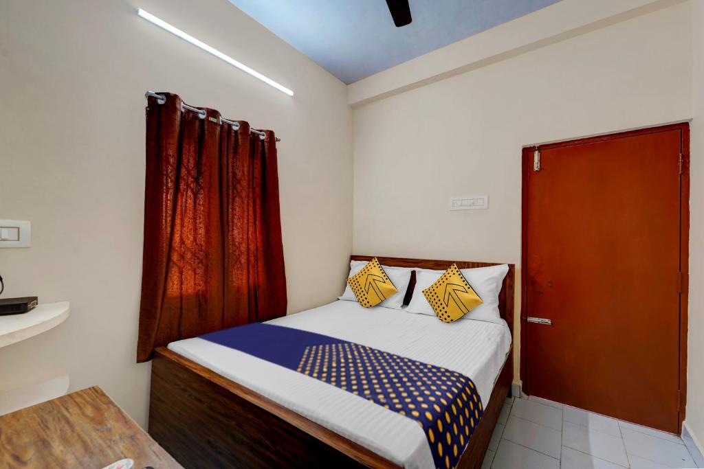 a small bedroom with a bed and a red door at SPOT ON RKH Inn in Chennai