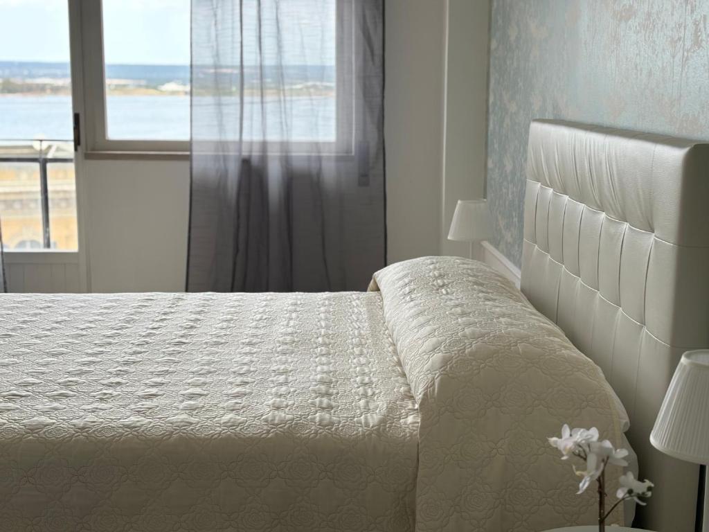 a white bedroom with a bed and a window at Acqua Holiday House in Taranto