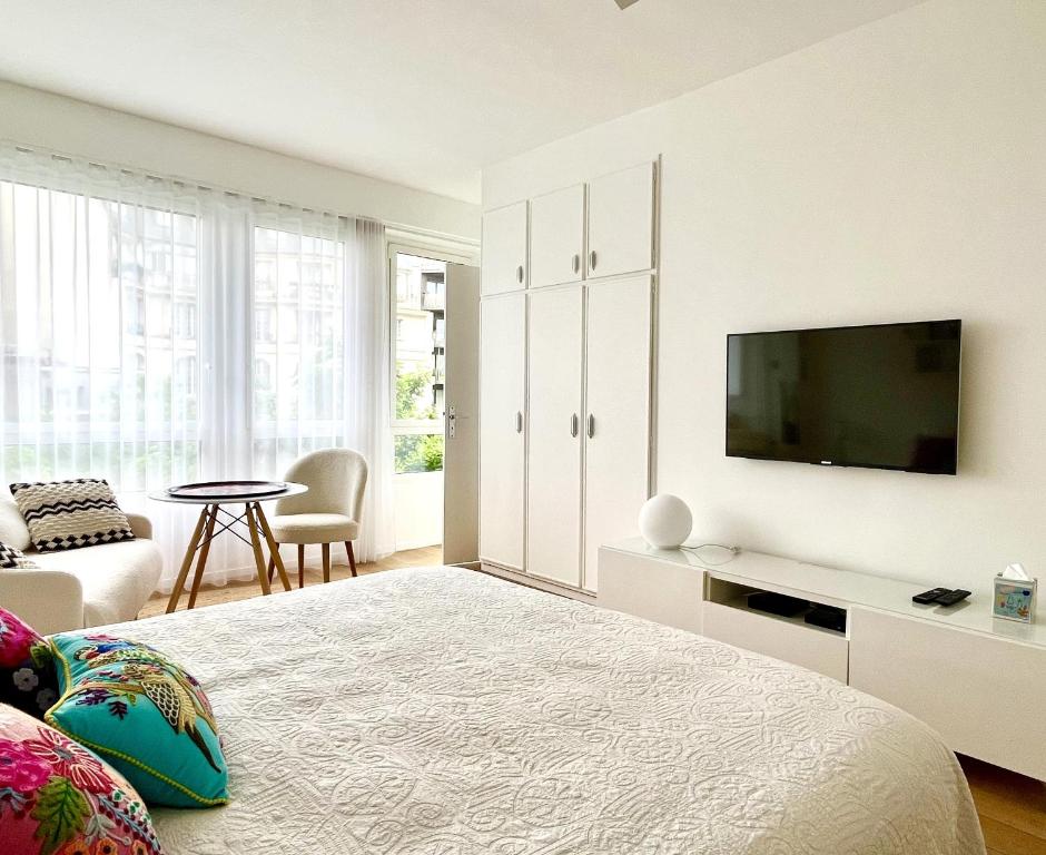 Montparnasse Studio Deluxe في باريس: غرفة نوم بيضاء مع سرير وتلفزيون بشاشة مسطحة
