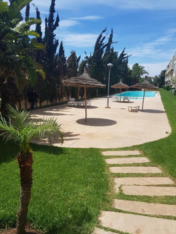 a walkway leading to a pool with umbrellas and grass at Beach-Side 2-BR Oasis with Private Pool & Parking in Casablanca