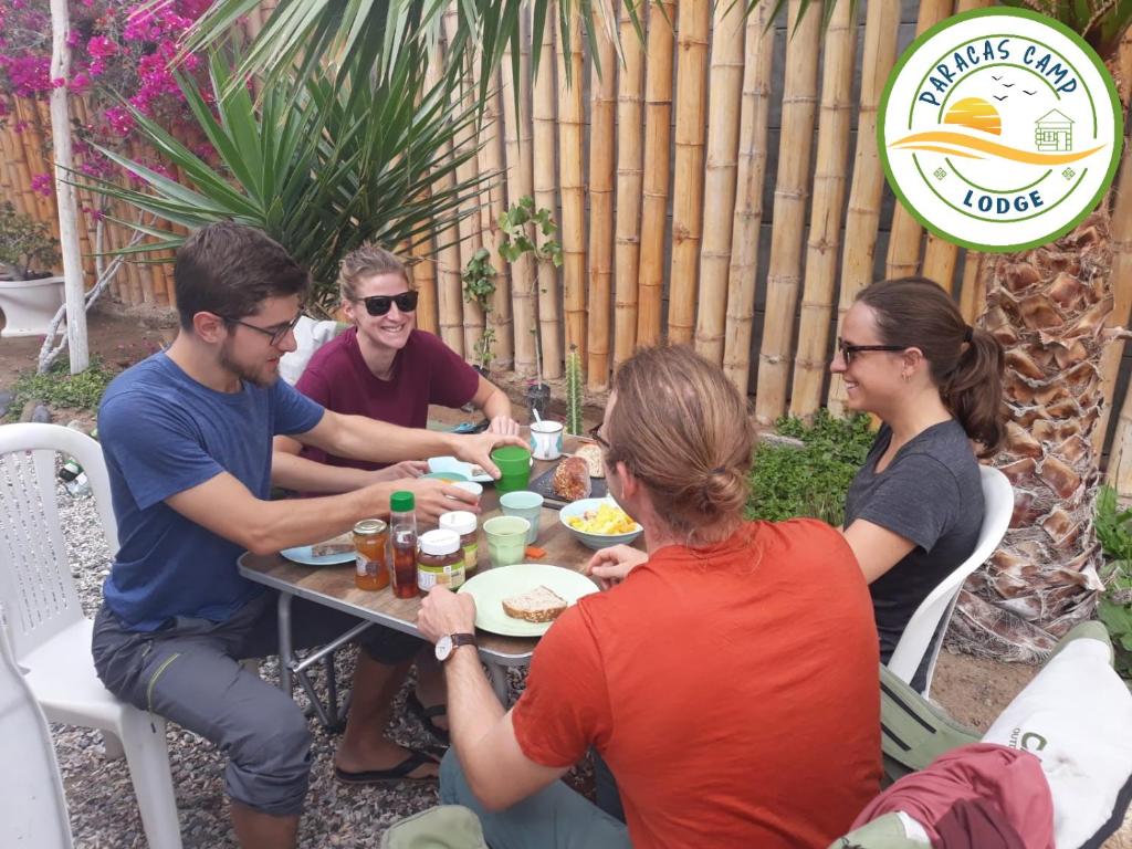 パラカスにあるParacas Desert Lodge&Toursのテーブルの周りに座って食事をとる人々のグループ