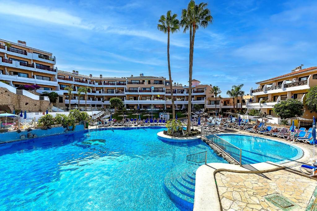 a resort with a large pool with chairs and palm trees at Ocean View Apartment in Albatros Golf del Sur in San Miguel de Abona