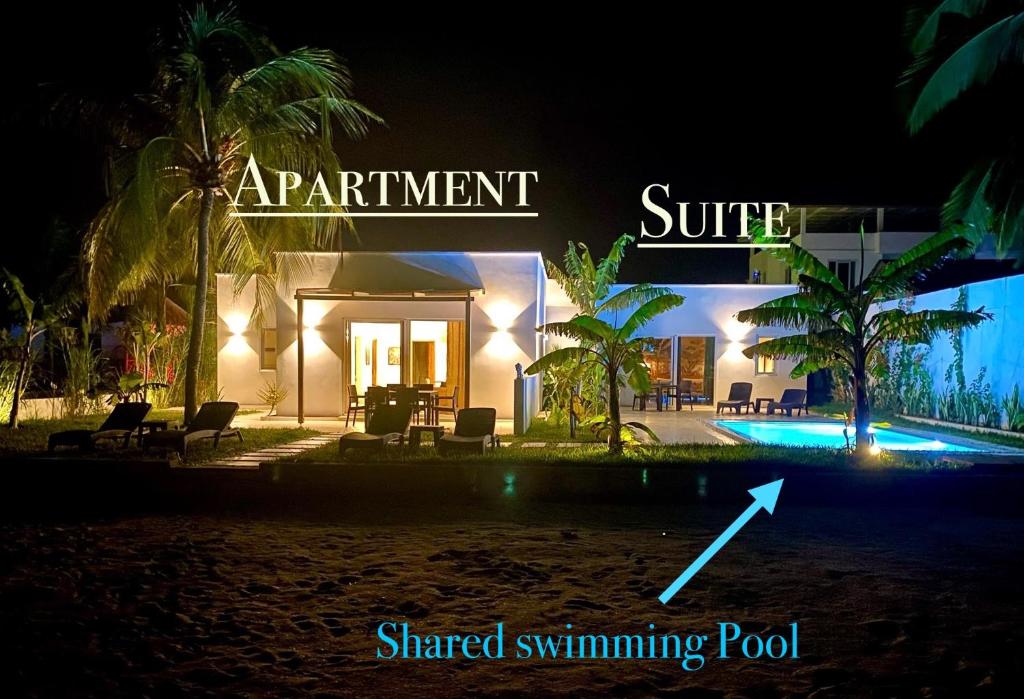 Bunju的住宿－Lions Zanzibar SUITE&APARTEMENT with private pool - LUXURY ON THE SEASIDE，享有度假村的夜景,设有阅读迷人的冲浪共用游泳池的标志