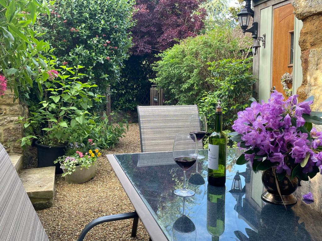 Chideock的住宿－The Burrow，一张桌子,上面放着两杯葡萄酒和紫色的鲜花