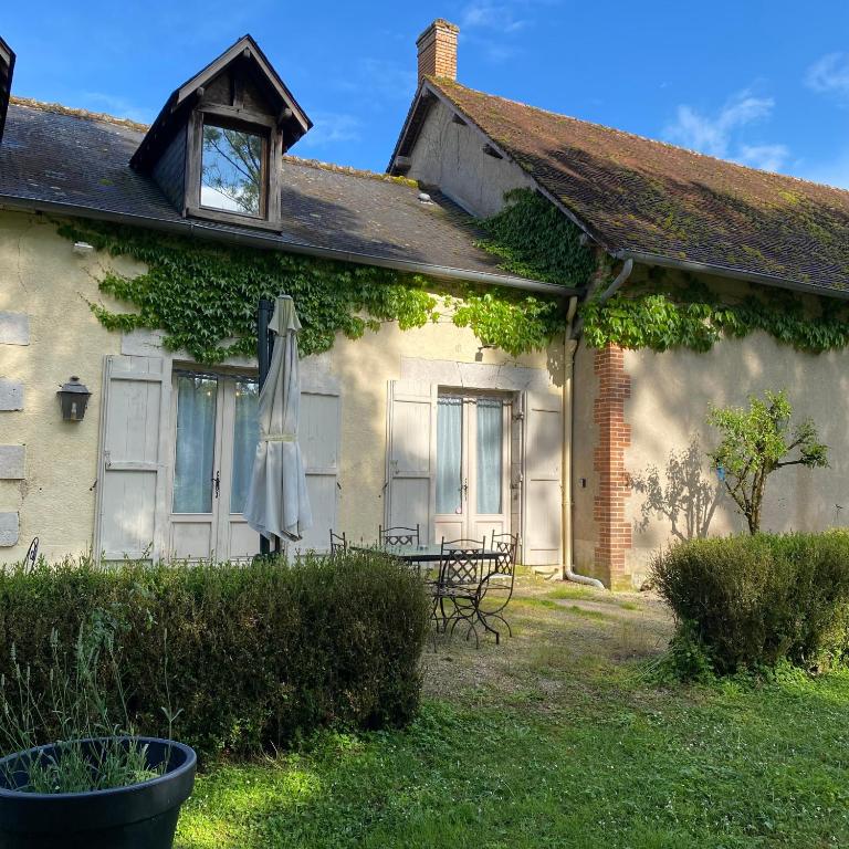 une maison avec un parapluie à l'extérieur dans l'établissement Gîte du Prieuré de Corbrandes - Longère typique en pleine nature - Entre Chambord et Beauval, 6 pers, animaux OK, à Soings-en-Sologne