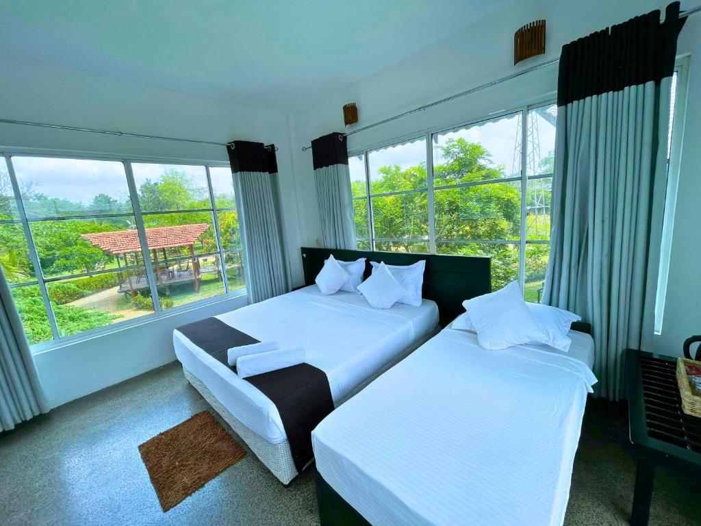 sypialnia z 2 łóżkami i dużym oknem w obiekcie Elephant Entrance w mieście Habarana