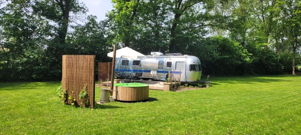 a rv parked in a field in a yard at Glamping aan de Maas in Kessel