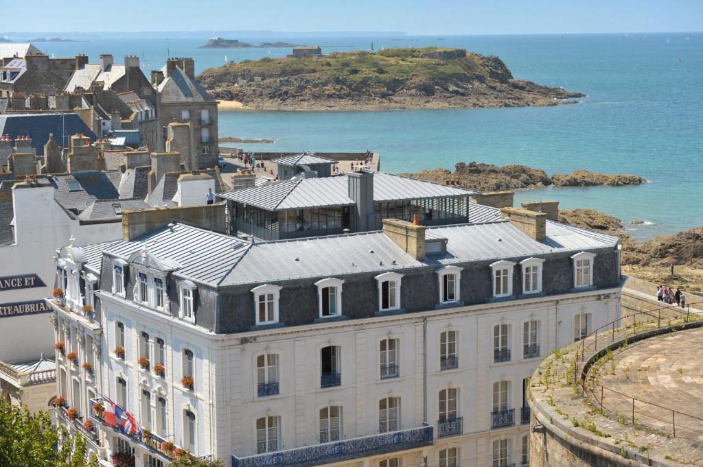 un grande edificio bianco vicino all'oceano di Hôtel France et Chateaubriand a Saint Malo