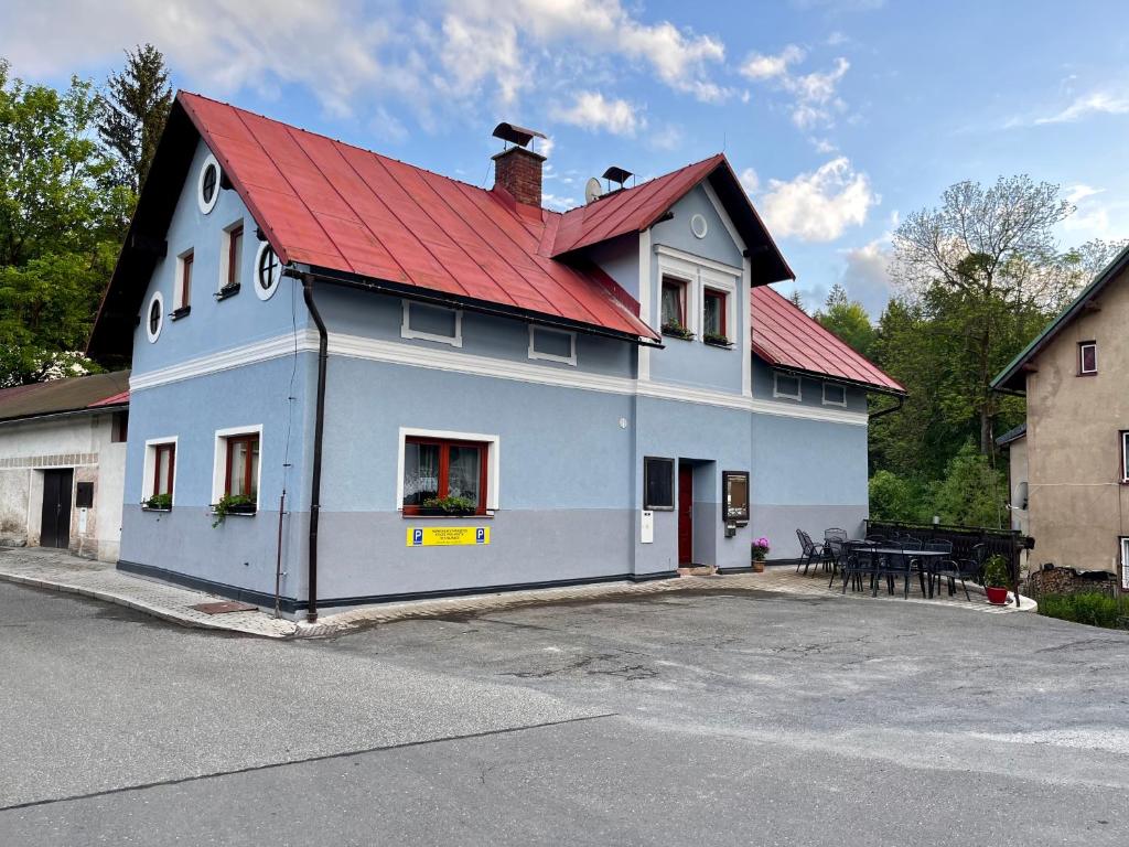 un edificio azul con techo rojo y mesa en Penzion U Zemánků, en Jablonec nad Jizerou