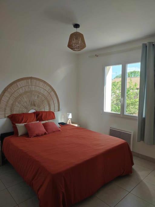 une chambre avec un grand lit avec une couverture rouge dans l'établissement Maison charmante à proximité de Luçon, à Les Magnils-Reigniers