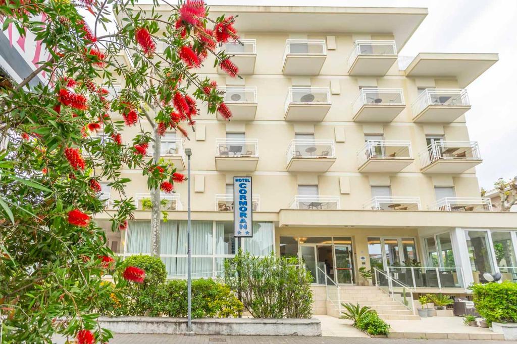 budynek z czerwonymi kwiatami przed nim w obiekcie Hotel Cormoran Riccione w mieście Riccione