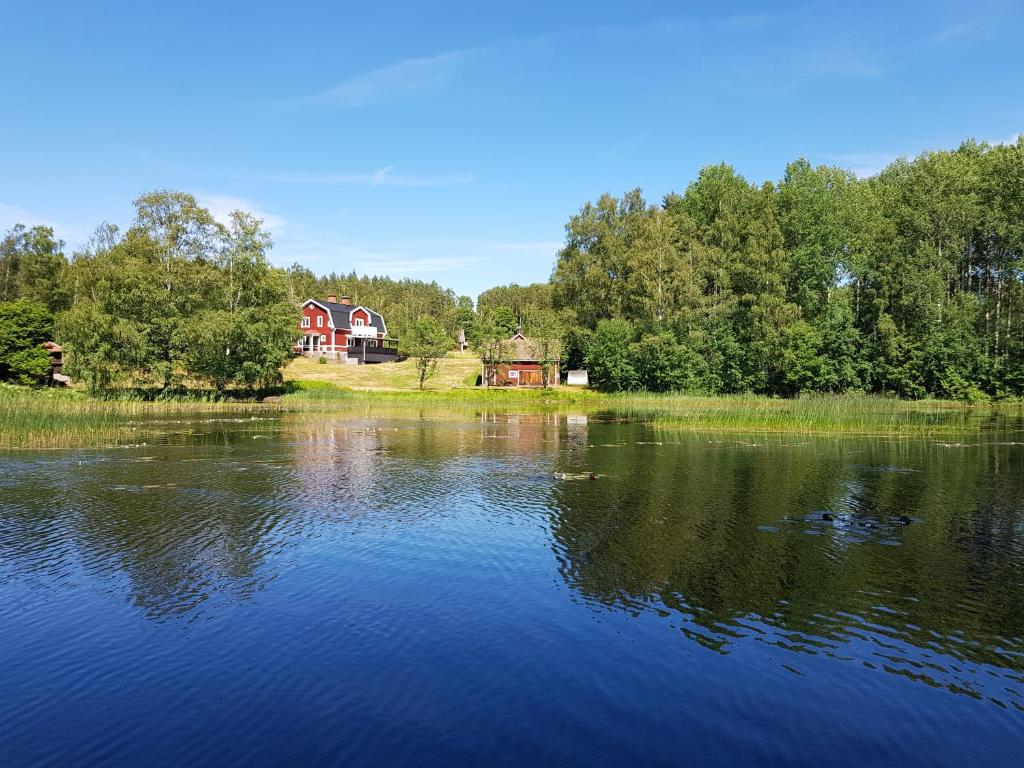 a large lake with a red house in the background at Landhaus Lönneberga in Lönneberga