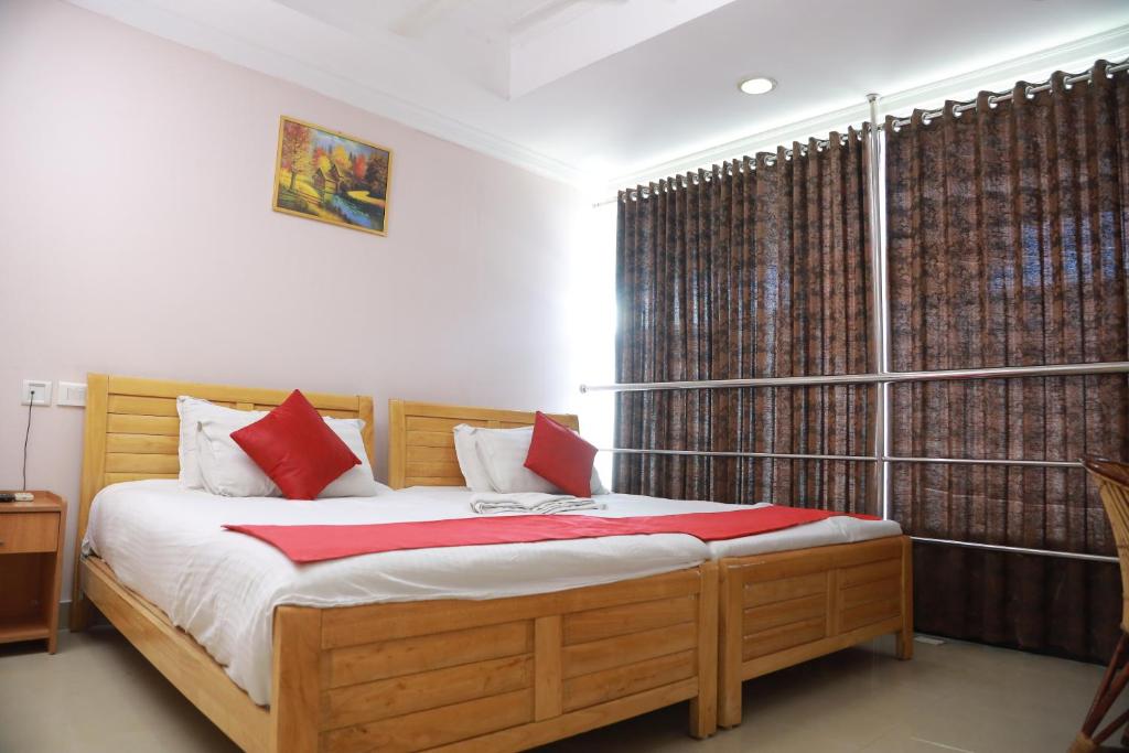 Collection O Safe Hotel Kadavanthra في إرناكولام: غرفة نوم بسرير ومخدات حمراء ونافذة