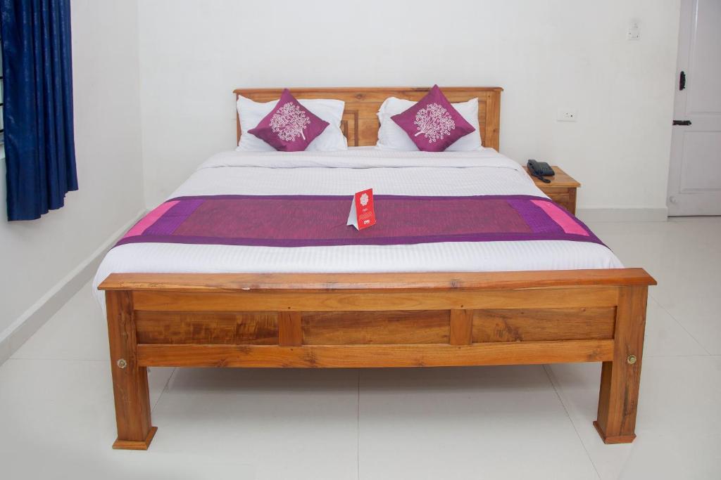 uma cama com uma estrutura de madeira com lençóis roxos e brancos em Flagship Key 2 Heaven em Ooty