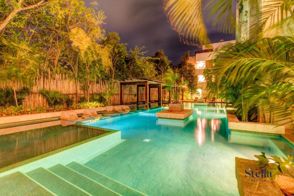 a large swimming pool in a building with trees at Private Rooftop 1BR Condo with Stunning Common Areas in Tulum