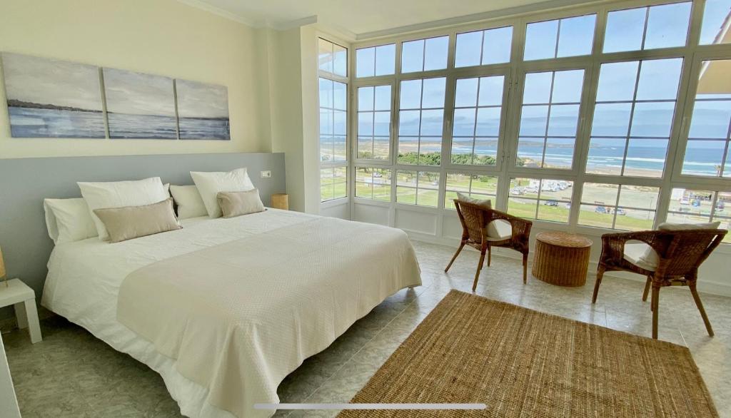 a bedroom with a large bed and a table with chairs at Casa en 1ª línea del mar - House on Sea Front Valdoviño in Valdoviño