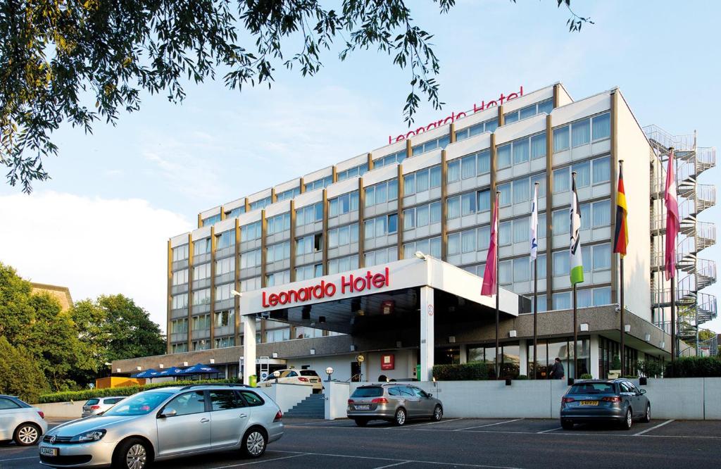 een hotel met auto's geparkeerd op een parkeerplaats bij Leonardo Hotel Mönchengladbach in Mönchengladbach