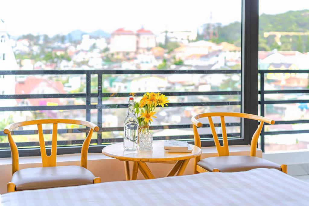 uma mesa com duas cadeiras e uma mesa com flores em VX Hotel em Da Lat