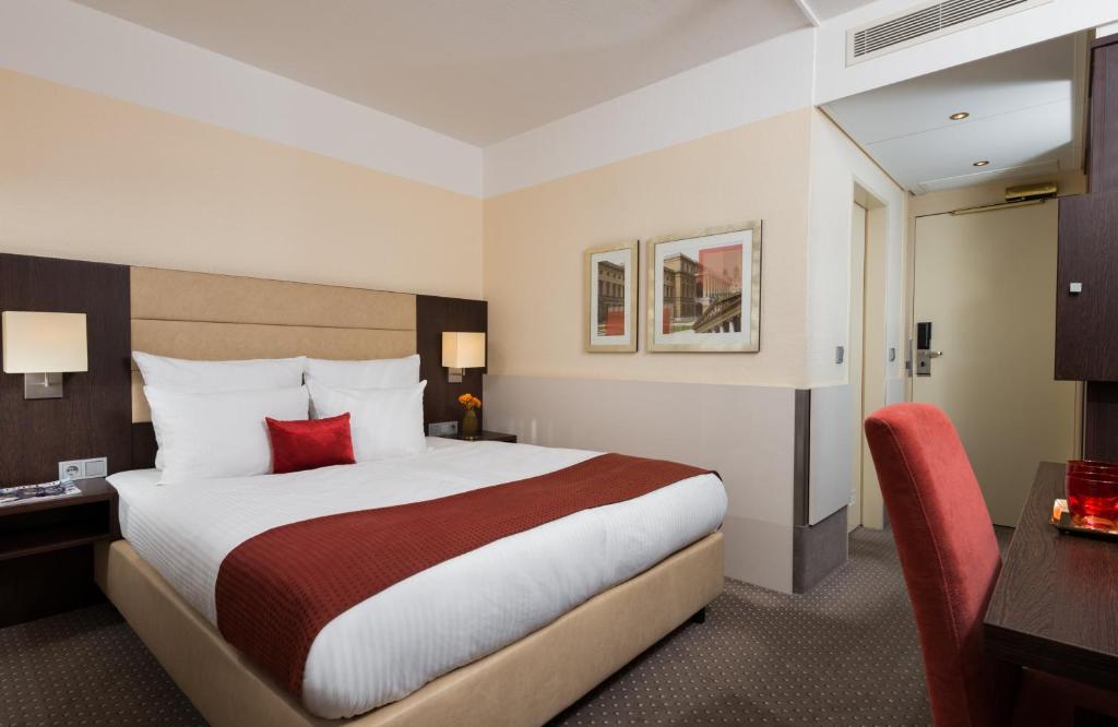 um quarto de hotel com uma cama grande e uma secretária em Leonardo Hotel Munich Arabellapark em Munique