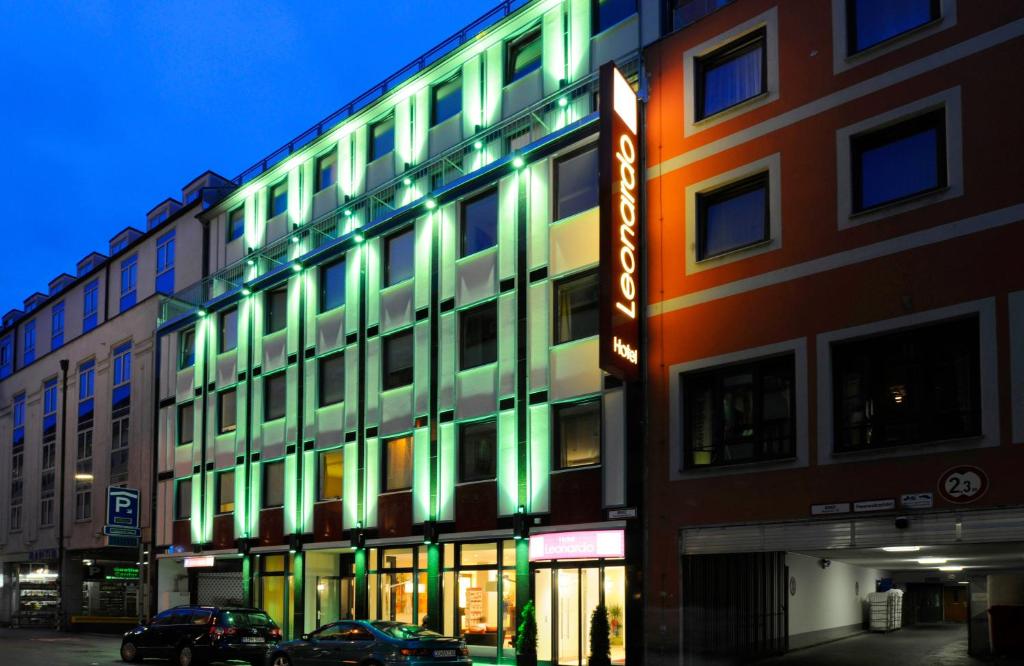a building with green lights on the side of it at Leonardo Hotel München City Center in Munich