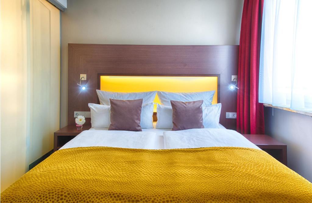a bedroom with a large bed with a yellow blanket at Leonardo Hotel München City Center in Munich