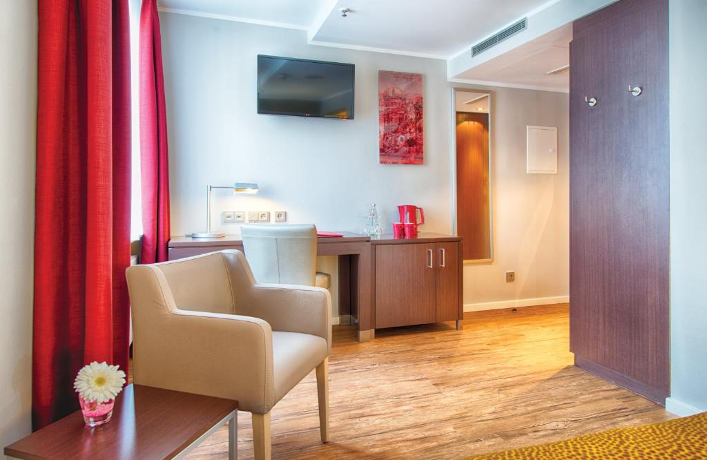a living room with a chair and a table at Leonardo Hotel München City Center in Munich