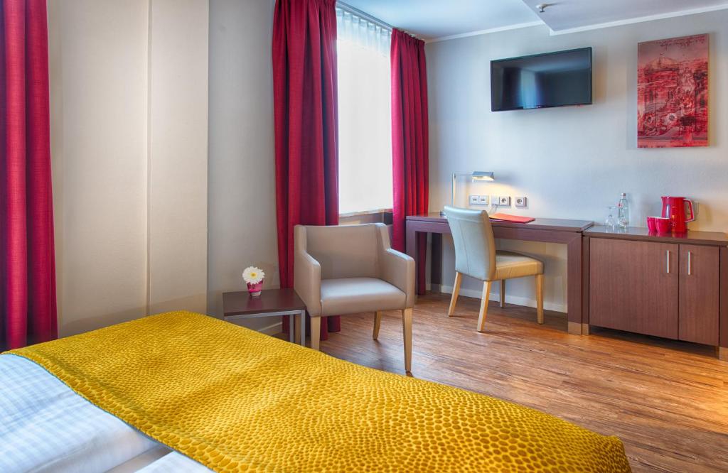 a hotel room with a bedroom with a desk and a bed at Leonardo Hotel München City Center in Munich