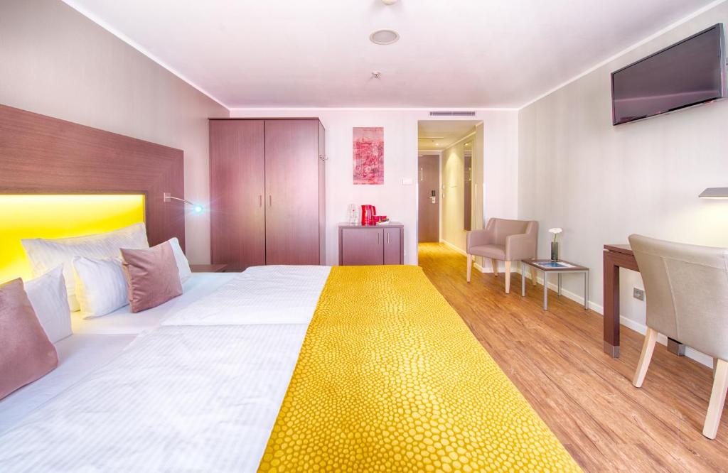 a hotel room with a large bed and a desk at Leonardo Hotel München City Center in Munich