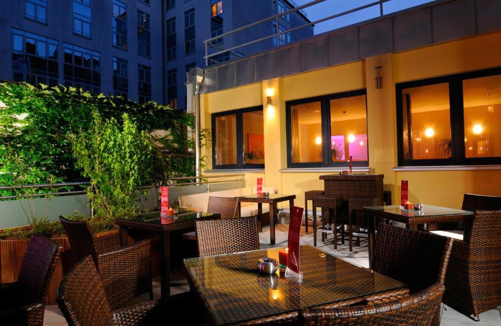 an outdoor restaurant with tables and chairs and windows at Leonardo Hotel München City Center in Munich