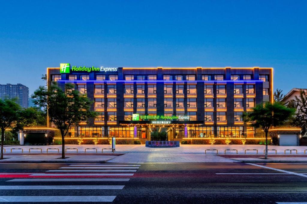 a hotel building with a blue lit up sign at Holiday Inn Express Langfang Yanjiao, an IHG Hotel in Langfang