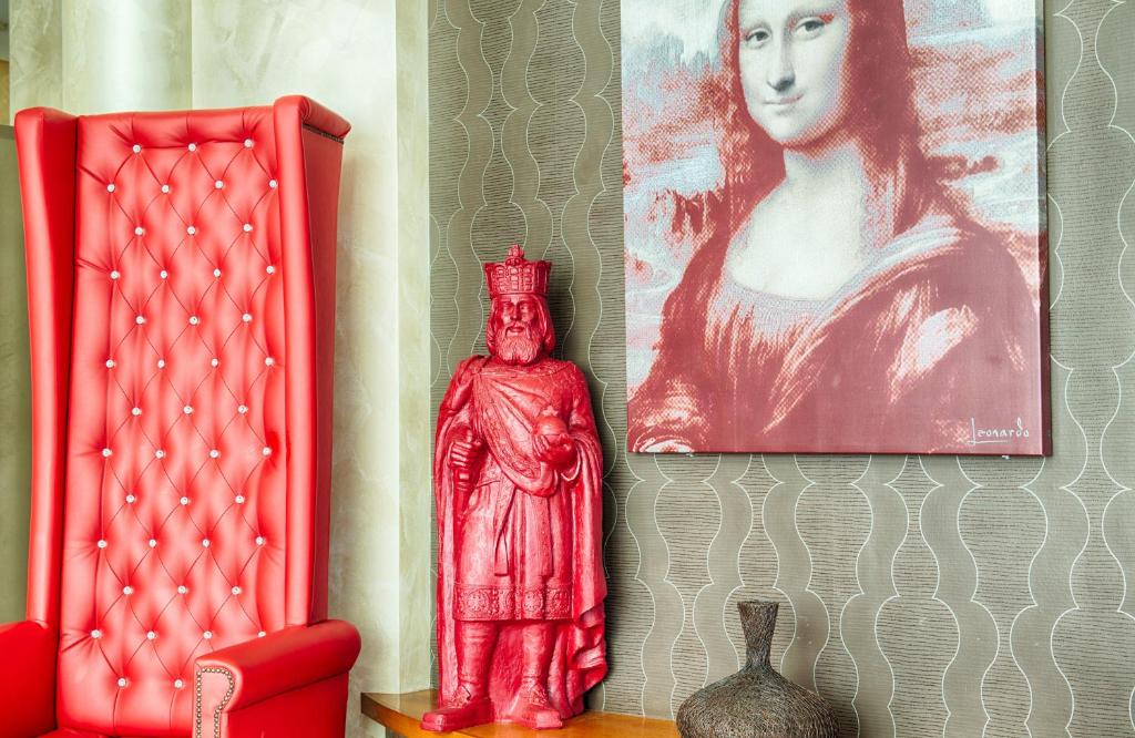 una estatua roja junto a una foto de una mujer en Leonardo Hotel Aachen, en Aachen