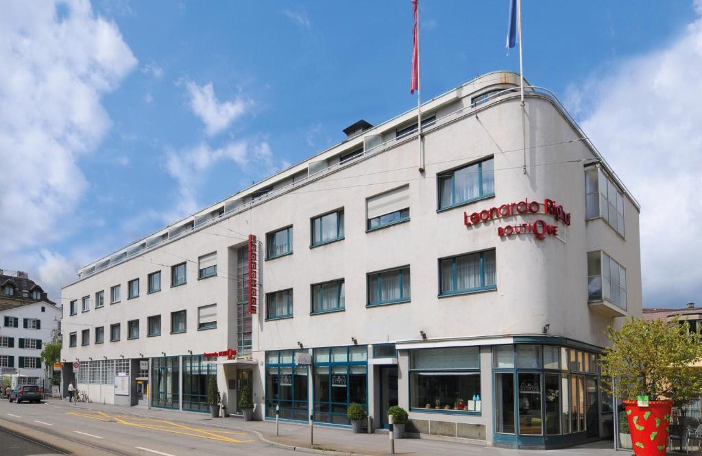 a white building with a red sign on it at Leonardo Boutique Hotel Rigihof Zurich in Zurich