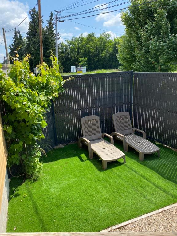 une cour arrière avec deux chaises et un banc sur l'herbe dans l'établissement Maison aux pieds des Alpilles, à Noves