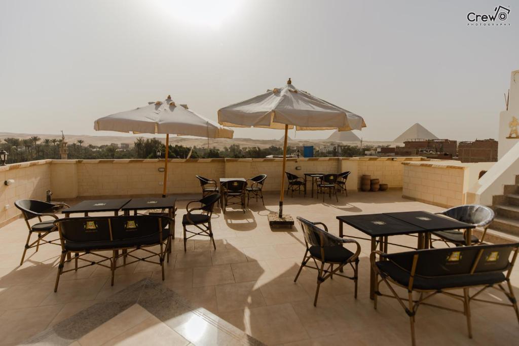 a patio with tables and chairs and umbrellas on a roof at Pyramids Golden Gate Hotel - Full Pyramids View & Roof Top in Cairo