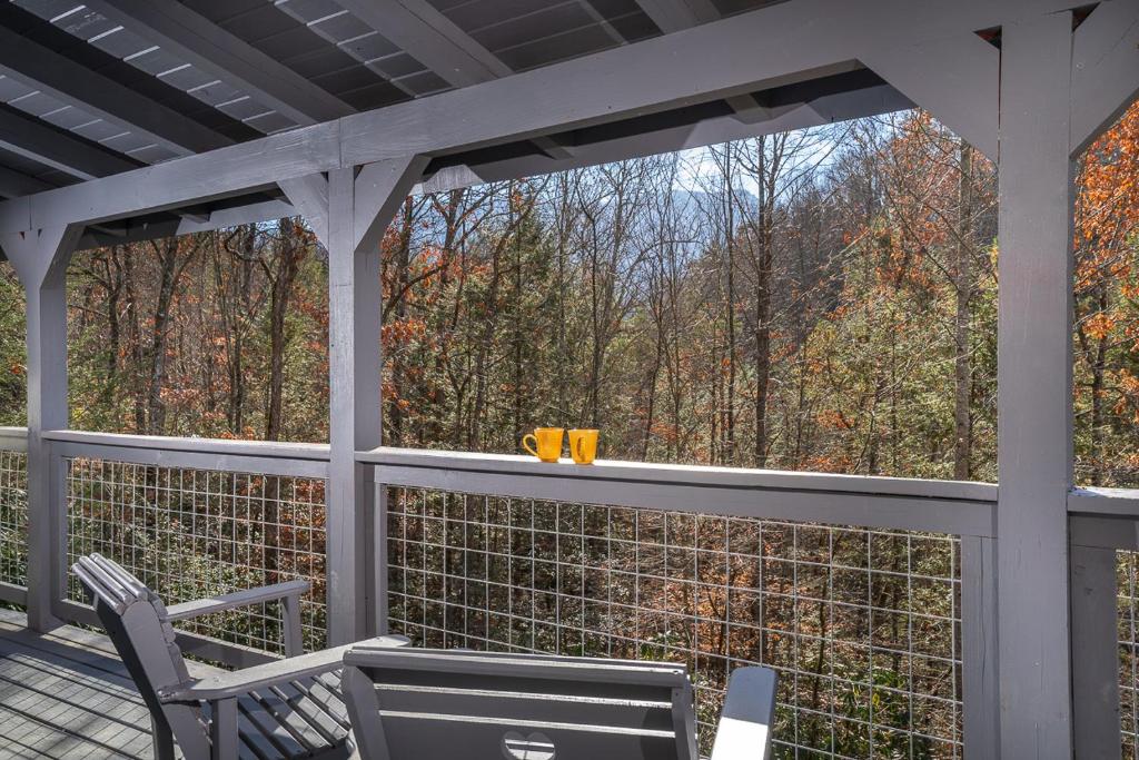 a screened porch with chairs and a view of the woods at Bear Necessity by Stony Brook Cabins in Gatlinburg