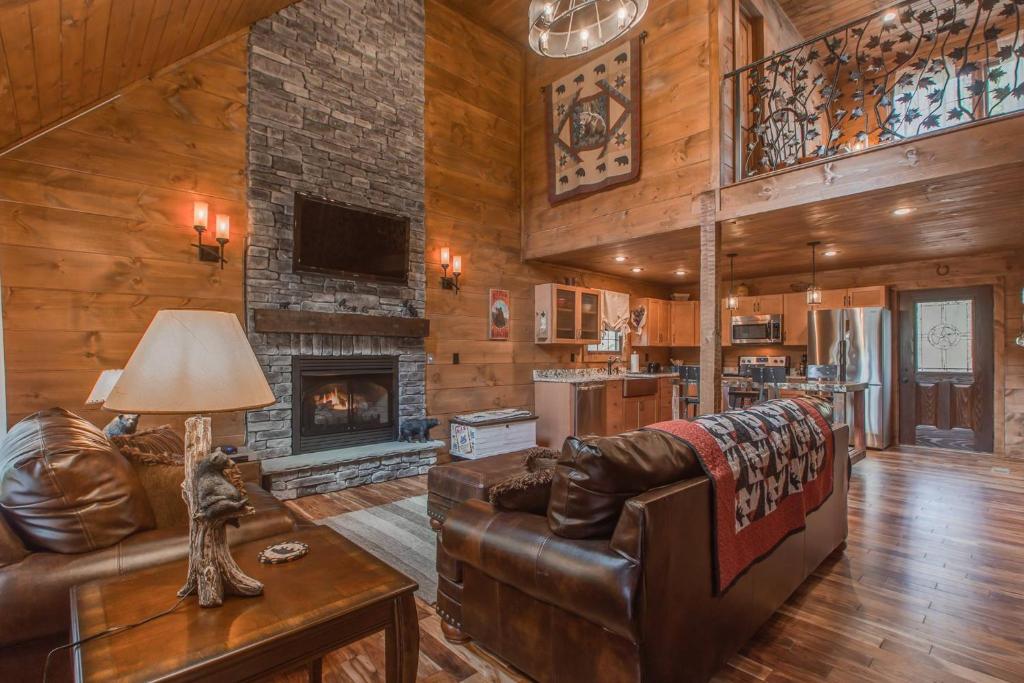 a living room with a leather couch and a fireplace at Black Bear Cabin by Stony Brook Cabins in Gatlinburg