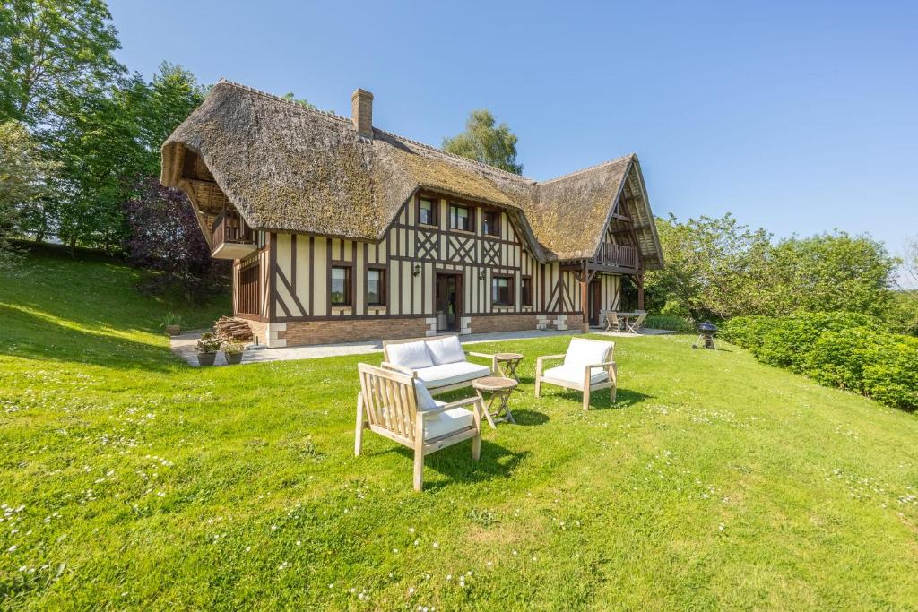 une maison avec deux chaises et une table dans la cour dans l'établissement Le Domaine des Colombages - Welkeys, à Barneville-la-Bertrand