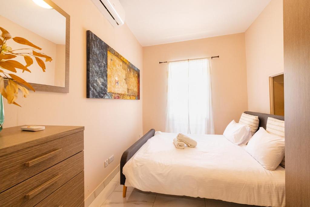 a small bedroom with a bed and a window at Happiness in Qormi
