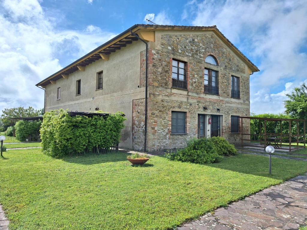 un gran edificio de piedra con un patio con césped en LaCollinaTuscany between San Gimignano and Volterra en Volterra