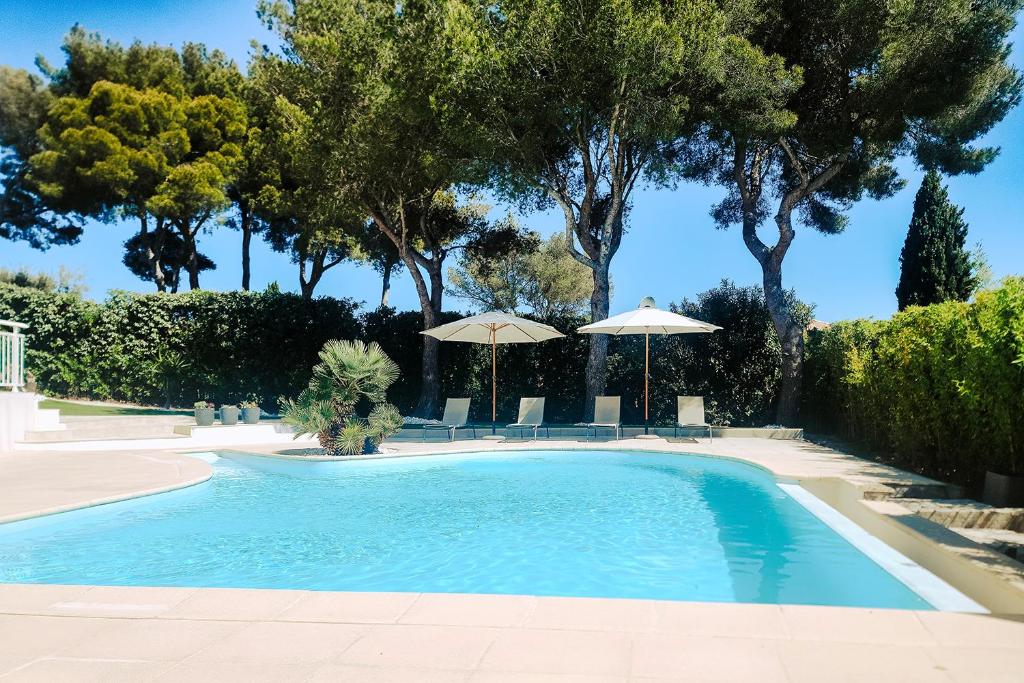 una piscina con sombrillas, sillas y árboles en LA VILLA ALBA, en Les Issambres