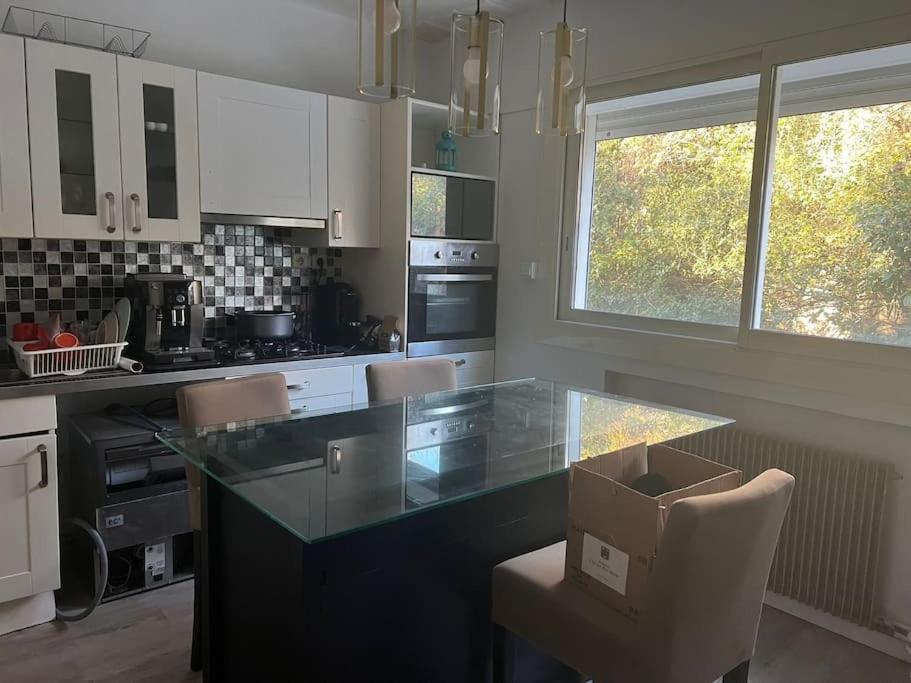 a kitchen with a glass counter and chairs in it at Bas de villa avec grande piscine in Marseille