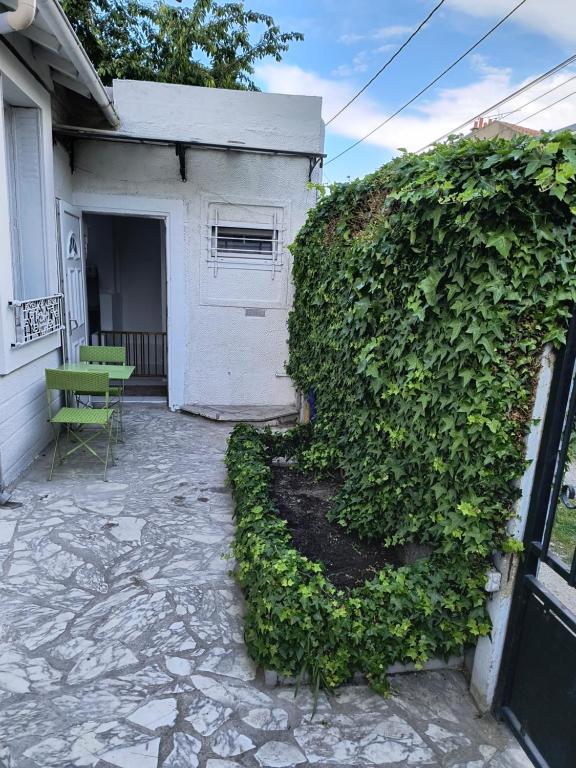 un mur couvert de lierre à côté d'un bâtiment avec une porte dans l'établissement Jolie Appartement indépendant, à Épinay-sur-Seine