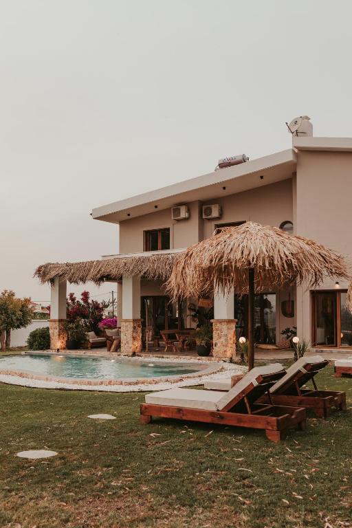 a resort with a pool and a straw umbrella at Maya pool & mountain view villa in Koskinou