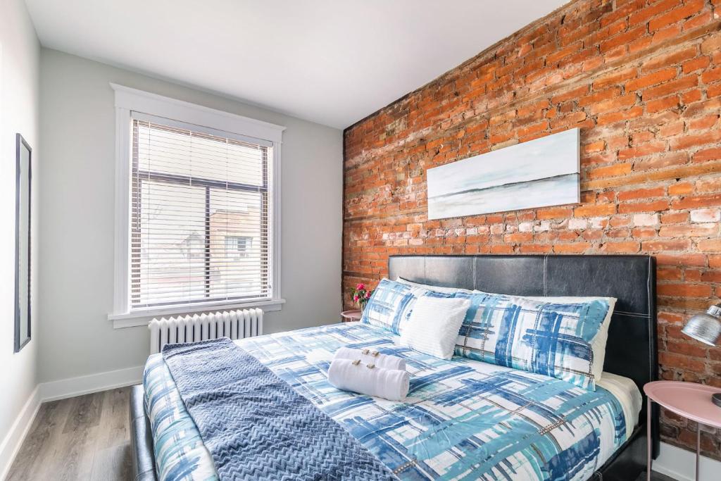 ハミルトンにある1BR Apt in Hamilton's Best Neighbourhoodのレンガの壁とベッドが備わるベッドルーム1室が備わります。