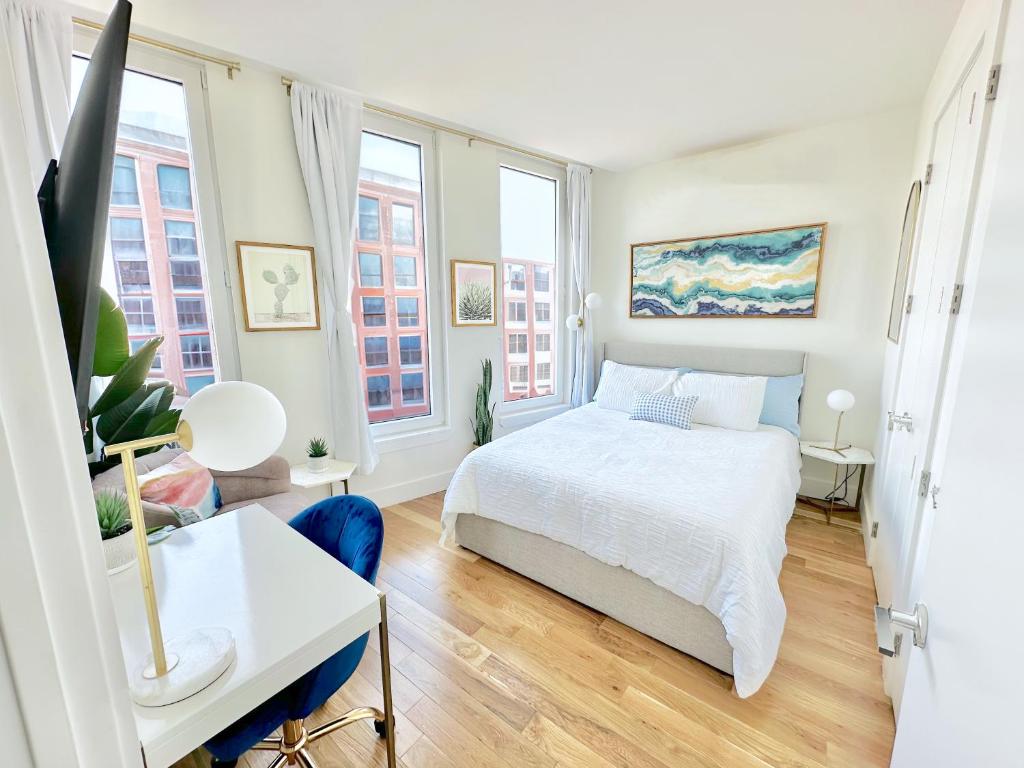 a bedroom with a bed and a desk and two windows at Large One Bedroom - Massive Private Terrace - Luxury Building - Williamsburg - Greenpoint in Brooklyn
