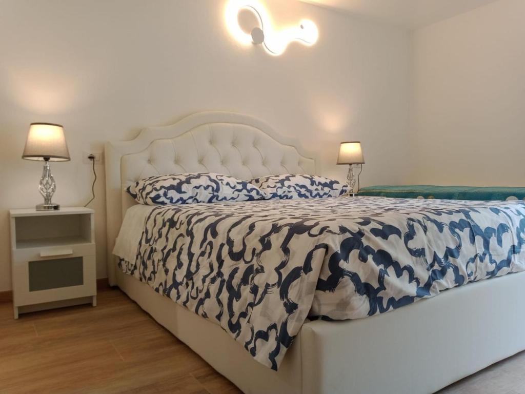 um quarto com uma cama branca com edredão azul e branco em La Grotta em Urzulei