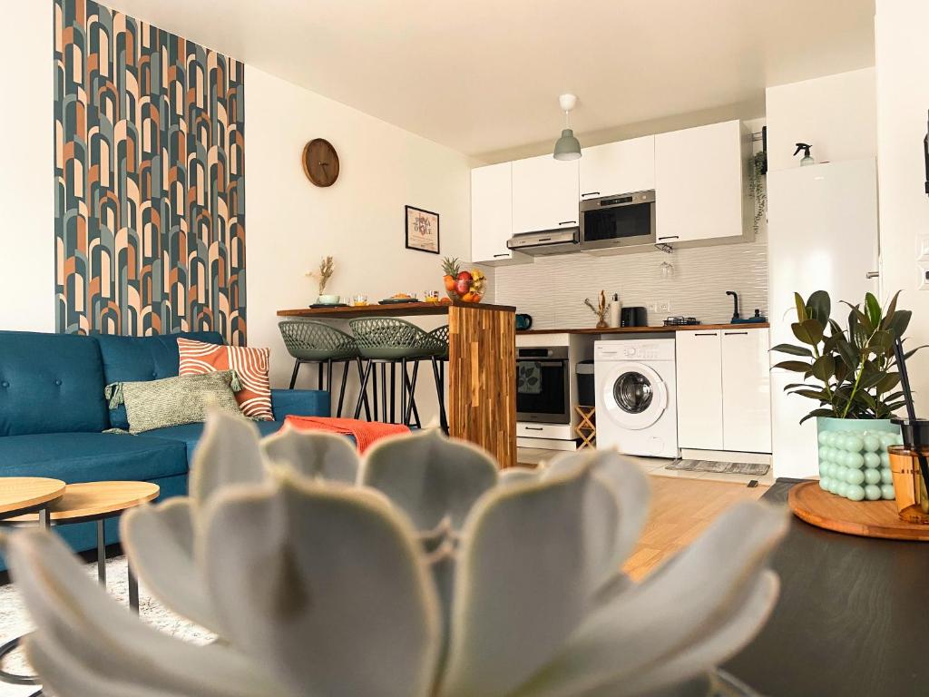 a living room with a blue couch and a kitchen at Le Refuge Urbain in Villejuif