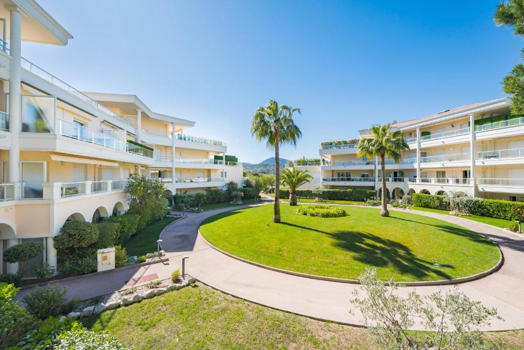 un immeuble d'appartements avec un parc et des palmiers dans l'établissement Appartement au Riviera Golf Domaine de Barbossi, à Mandelieu-la-Napoule