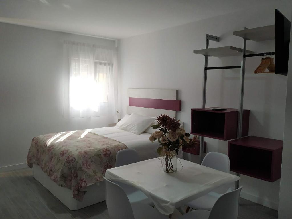 um quarto com uma cama e uma mesa com um vaso de flores em ALAUDAE APARTAMENTOS em Mérida